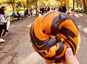 Person holding a black and orange marbled bagel