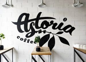 White brick wall with Astoria Coffee logo on wall in black lettering