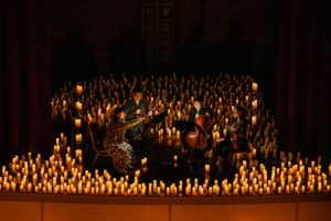 A string quartet performing with hundreds of candles around.
