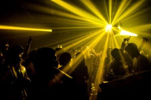 People dancing in a dark room with a yellow light shining off a disco ball at Good Room NYC