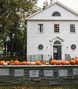 White building in Newport, Rhode Island with a stone fence and pumpkins on top of it