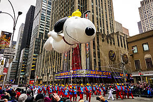 Snoopy balloon floats in the air during the annual Macy's Thanksgiving Day parade along Avenue of Americas with the Radio Music Hall in the background. Manhattan, New York, USA - November 27, 2014. 