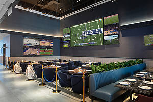 Booth seating with a flat screen TV on the wall playing a football game